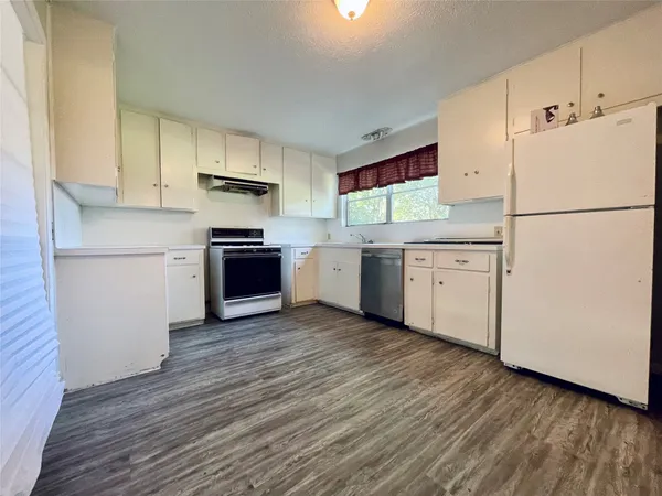 a kitchen with cabinets stainless steel appliances and wooden floor