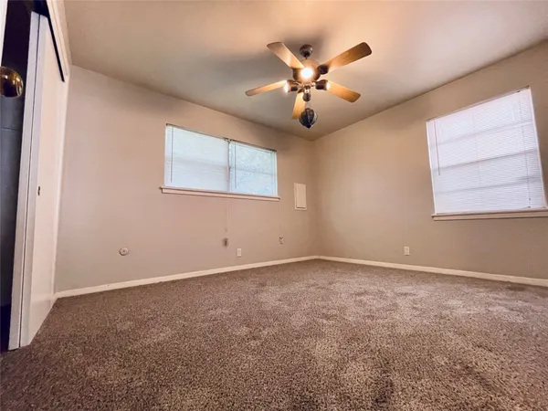 an empty room with windows and chandelier fan