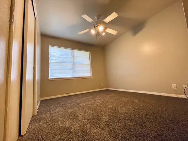 an empty room with windows and chandelier fan