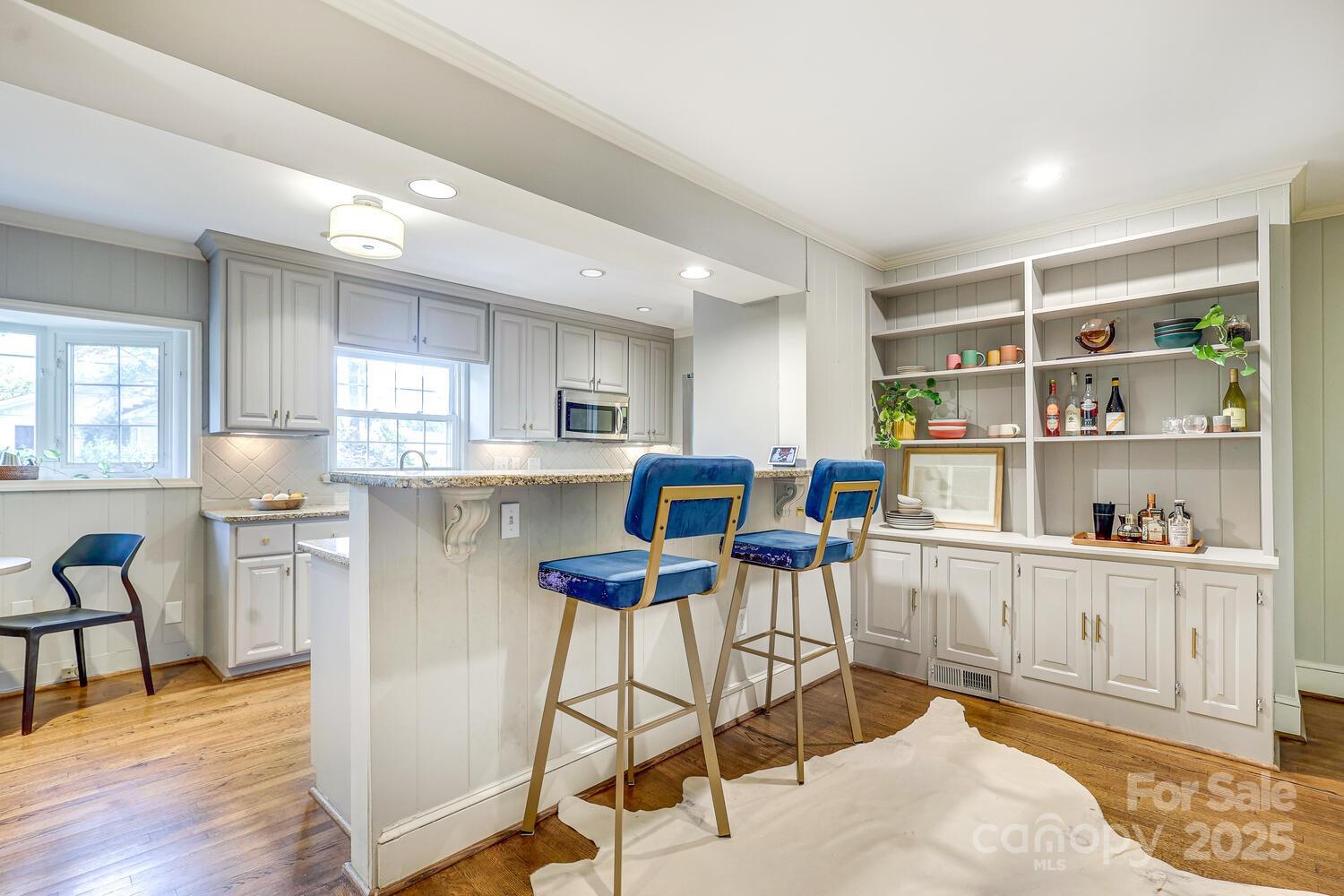 500 Ellsworth Road Charlotte, NC 28211 - Photo 12 of 40 a kitchen with stainless steel appliances kitchen island granite countertop a table chairs in it and wooden floors