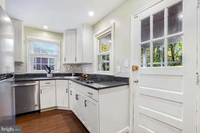 a kitchen with granite countertop white cabinets and white appliances