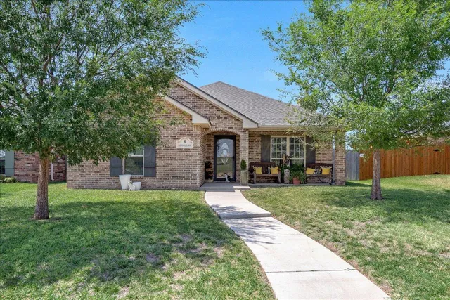 a front view of a house with a yard and trees