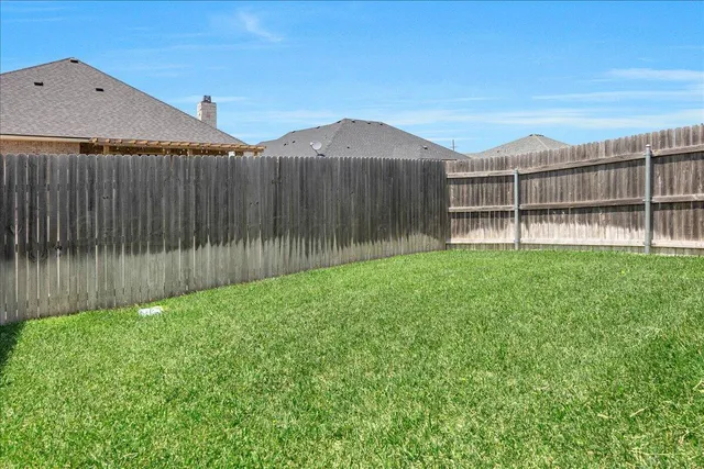 a backyard of a house with lawn chairs and wooden fence