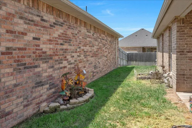 a view of a backyard with plants and brick wall