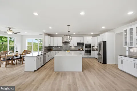 a living room with couches and kitchen view with wooden floor