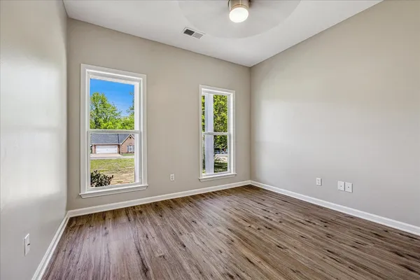 a view of an empty room with wooden floor and a window