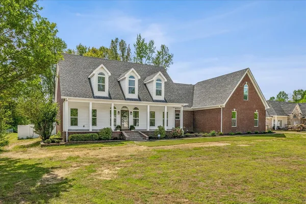 a front view of house with yard and trees in the background