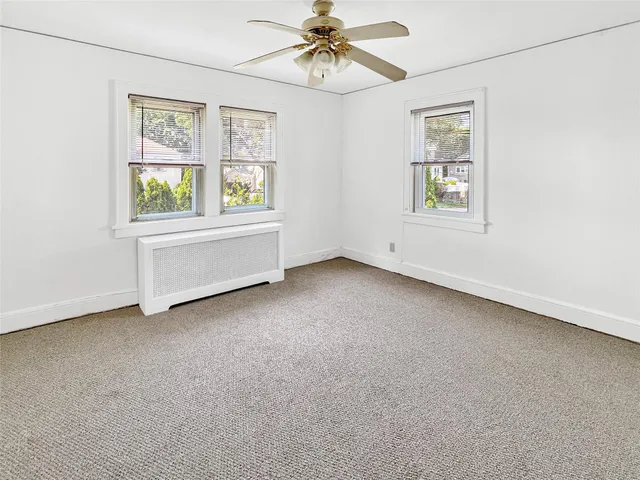 an empty room with windows and ceiling fan