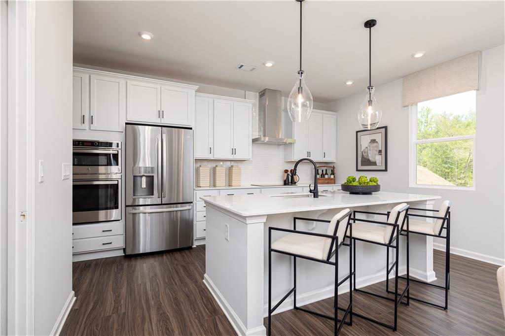 3260 Croftside Commons Powder Springs, GA 30127 - Photo 11 of 64 a kitchen with stainless steel appliances a stove a sink a refrigerator and white cabinets with wooden floor