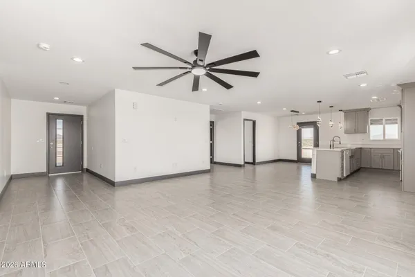 a view of a livingroom with furniture a ceiling fan and kitchen view
