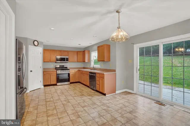 a large kitchen with granite countertop a stove a sink dishwasher a refrigerator and white cabinets with wooden floor