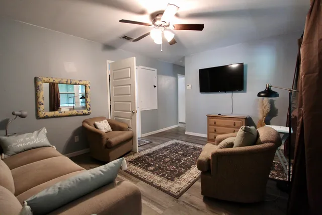 a living room with furniture a flat screen tv and a refrigerator