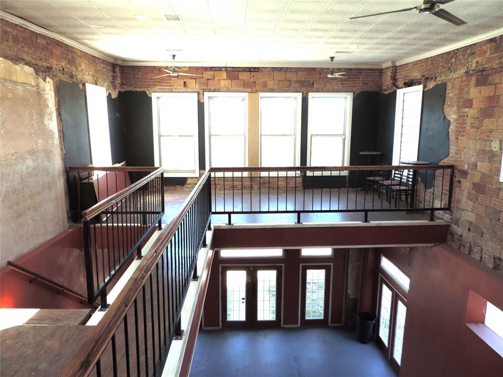 112 South Austin Street Ranger, TX 76470 - Photo 22 of 40 a view of staircase with two couches and large window with wooden floor