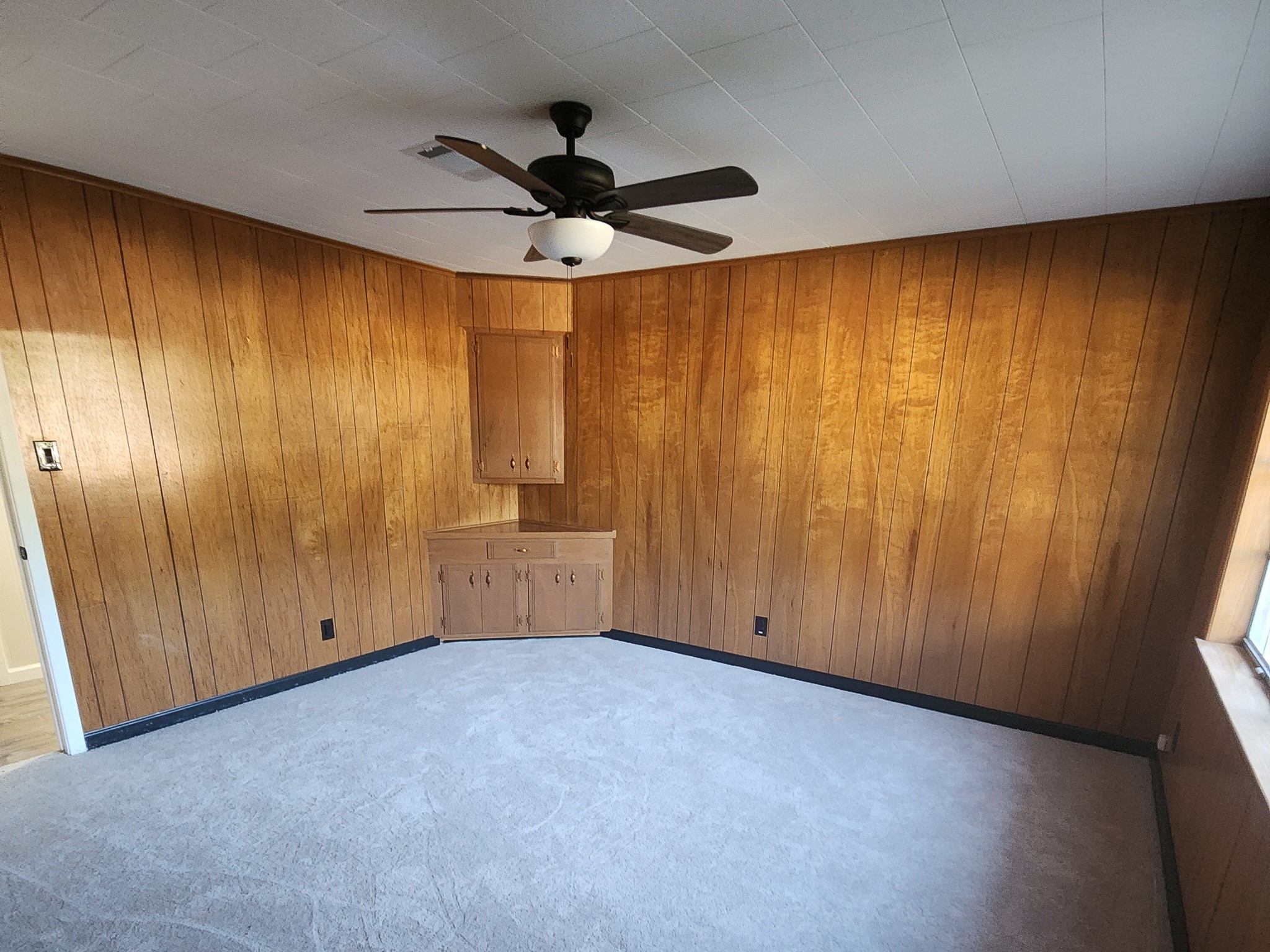 201 Verna Street Jasper, TX 75951 - Photo 17 of 27 This cozy secondary bedroom features rich wood paneling, a built-in cabinet, and the convenience of an attached half bath, perfect for comfort and privacy.