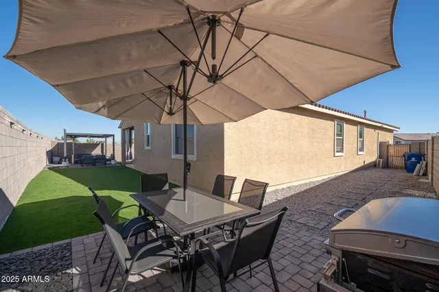 a view of a backyard with table and chairs under an umbrella