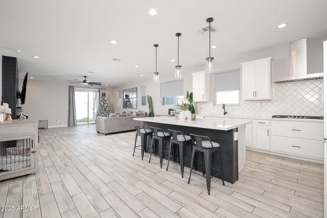 a kitchen with stainless steel appliances kitchen island granite countertop a sink dishwasher a stove and a dining table with wooden floor