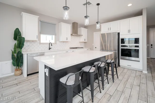 a kitchen with stainless steel appliances kitchen island a table chairs refrigerator and sink