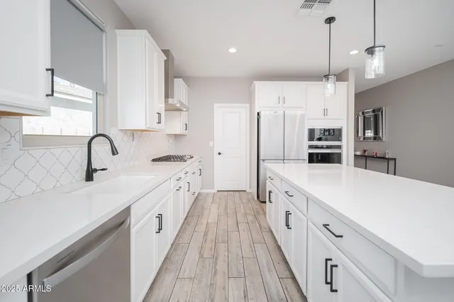 a large kitchen with stainless steel appliances lots of counter space a sink and a refrigerator