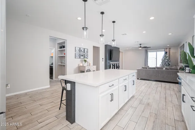 a large white kitchen with a large center island wooden floor and stainless steel appliances