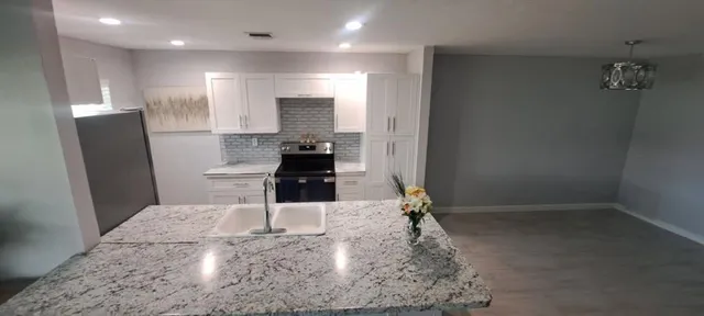 a kitchen with stainless steel appliances kitchen island granite countertop a refrigerator and a sink