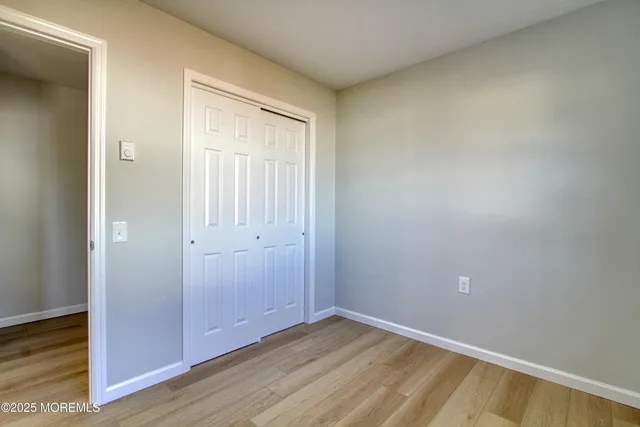 a view of an empty room with wooden floor and closet