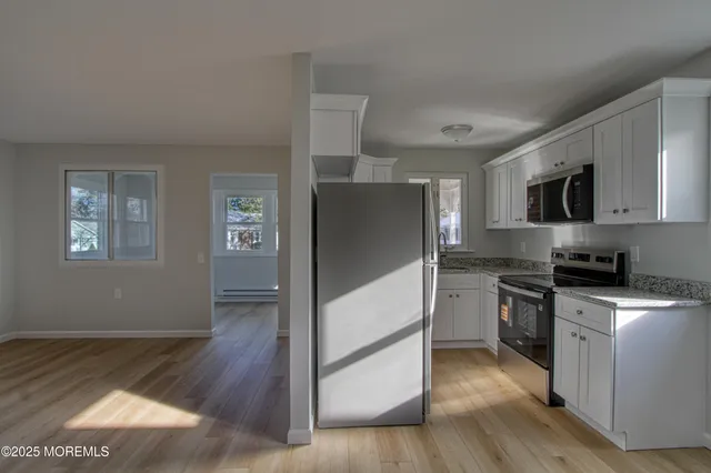 a kitchen with stainless steel appliances granite countertop a refrigerator a stove top oven a sink dishwasher and wooden floor