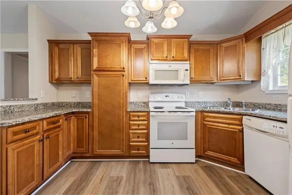 a kitchen with stainless steel appliances granite countertop a stove a sink dishwasher and a refrigerator with wooden floor