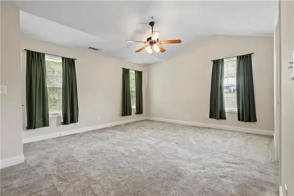a view of an empty room with window and chandelier fan