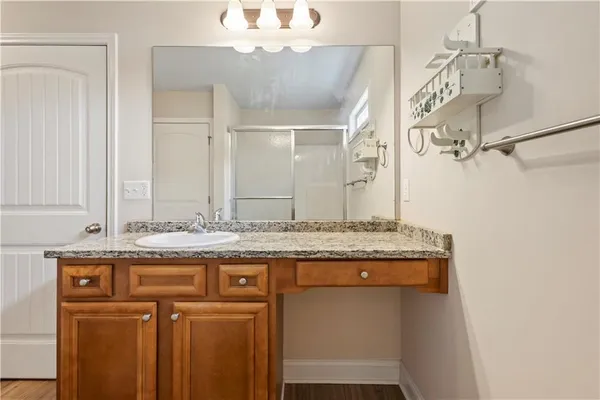 a bathroom with a granite countertop sink a mirror and a shower