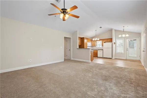 an empty room with a kitchen and a chandelier fan