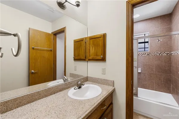 a bathroom with a granite countertop sink a mirror and shower