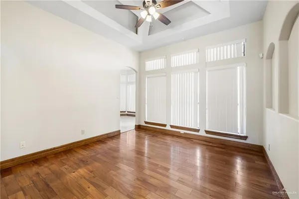 an empty room with wooden floor fan and windows