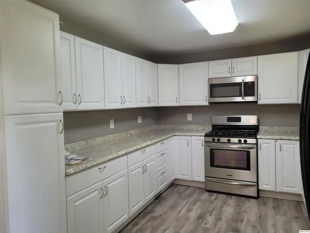 a kitchen with granite countertop white cabinets and stainless steel appliances