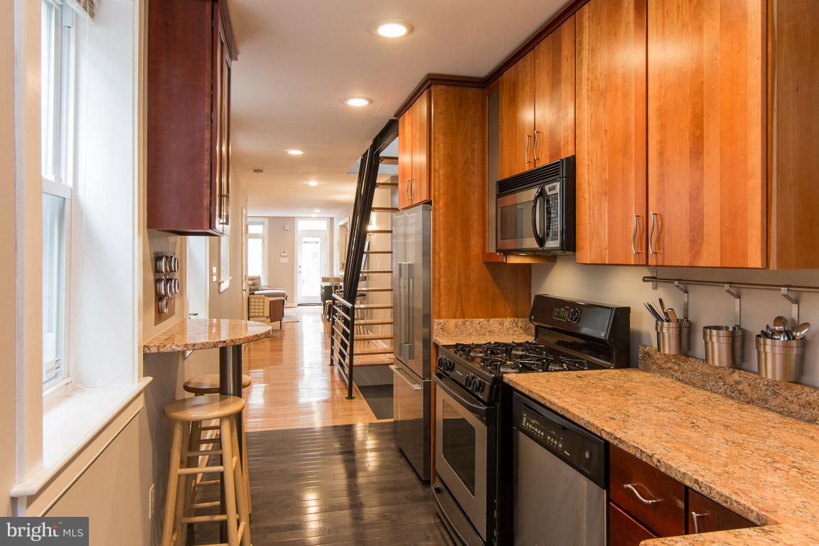 512 South Rose Street Baltimore, MD 21224 - Photo 15 of 30 a kitchen with stainless steel appliances granite countertop a stove top oven a sink dishwasher and wooden cabinets with wooden floor