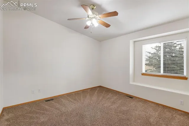 an empty room with a window and a ceiling fan
