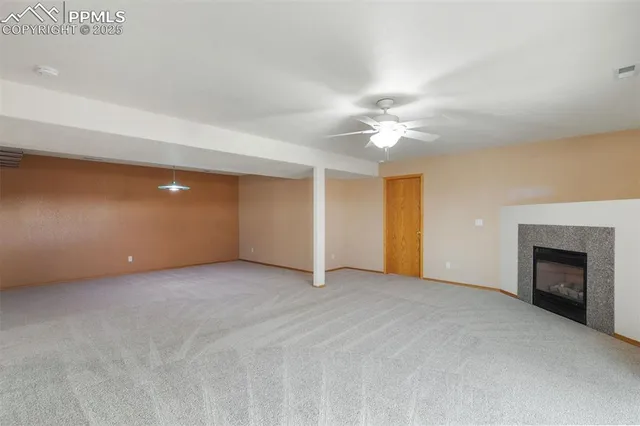 an empty room with a fireplace and a ceiling fan