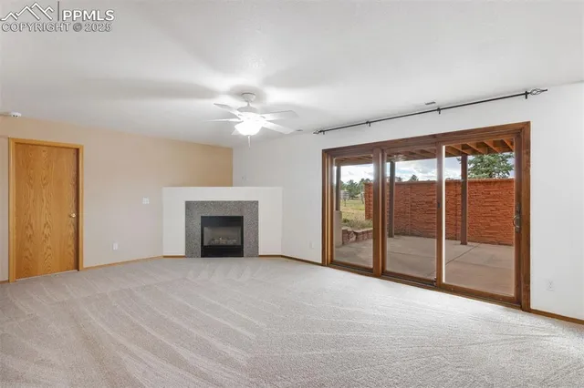 a view of an empty room with window and chandelier fan