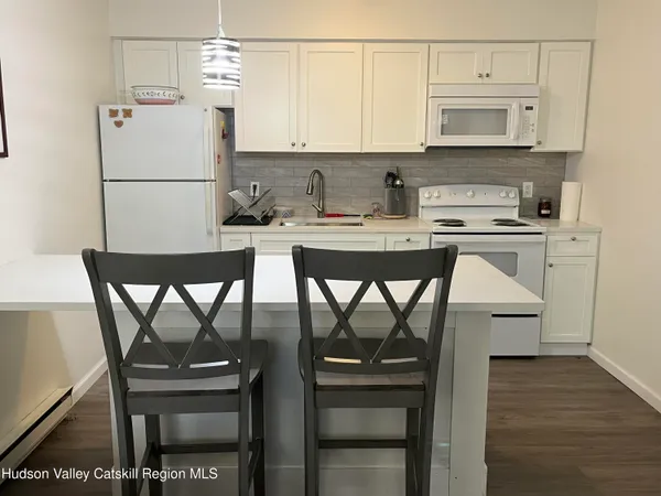 a kitchen with stainless steel appliances granite countertop a stove a refrigerator a microwave a dining table and chairs with wooden floor