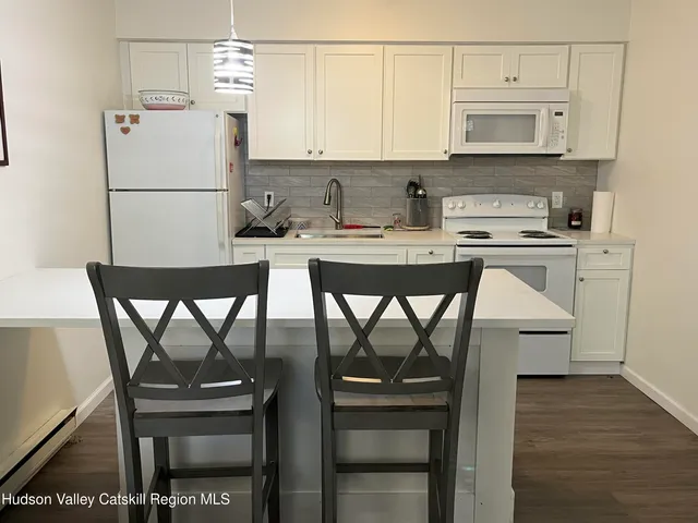 a kitchen with stainless steel appliances granite countertop a stove a refrigerator a microwave a dining table and chairs with wooden floor