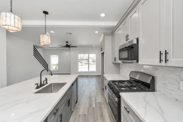 a kitchen with stainless steel appliances granite countertop a sink stove and refrigerator