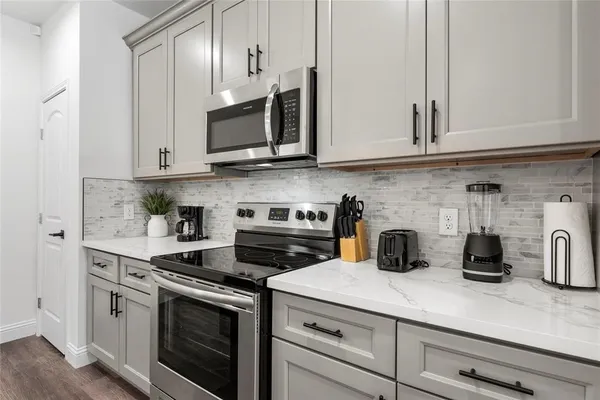a kitchen with stainless steel appliances granite countertop white cabinets a stove a sink and dishwasher
