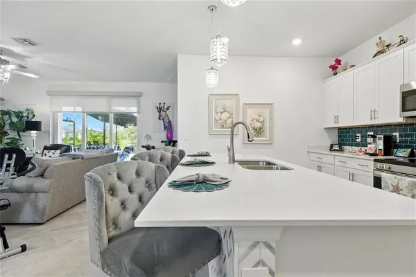 a large kitchen with granite countertop a stove a sink a dining table and chairs