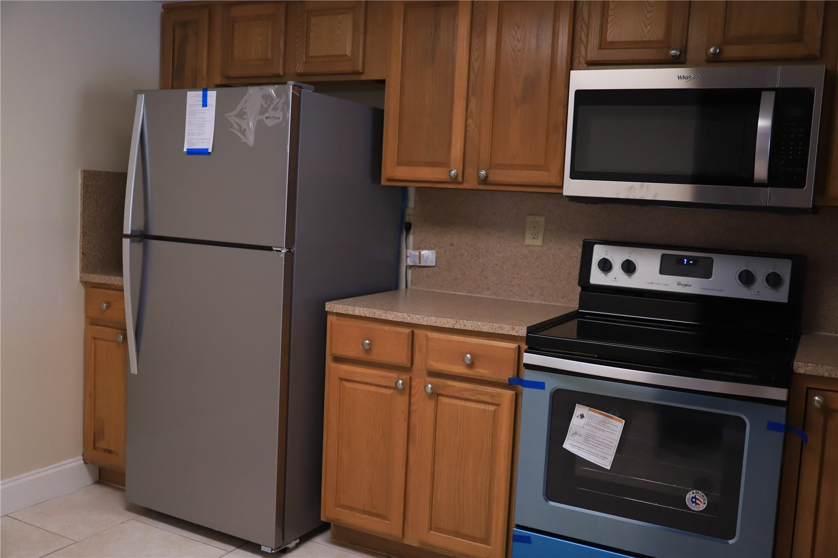 231 Southwest 113th Way, Unit 231 Pembroke Pines, FL 33025 - Photo 5 of 26 a kitchen with stainless steel appliances wooden cabinets and a stove top oven