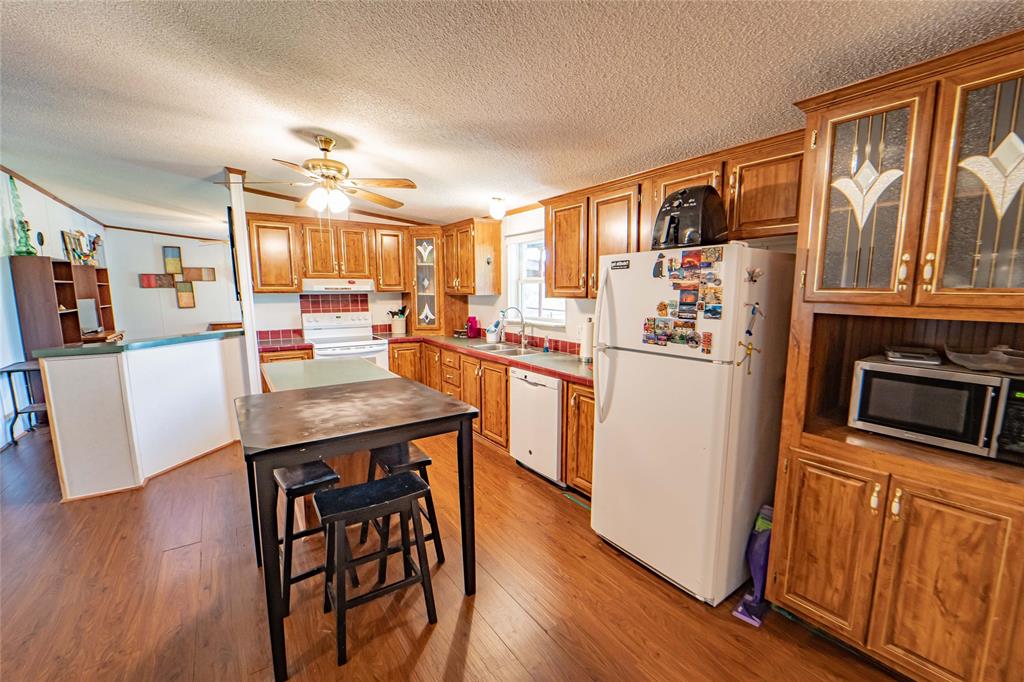 4942 County Road 206 Breckenridge, TX 76424 - Photo 20 of 40 a kitchen with stainless steel appliances granite countertop a refrigerator a stove top oven a sink dishwasher and wooden cabinets with wooden floor