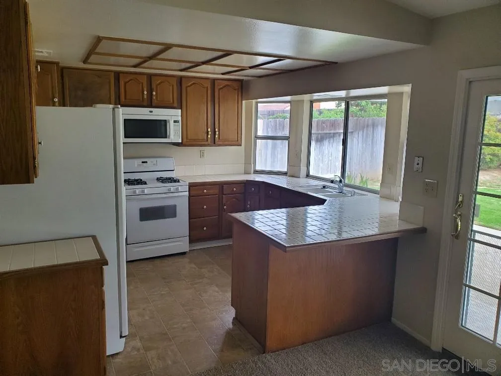 2708 Wind River Road El Cajon, CA 92019 - Photo 3 of 20 a kitchen with stainless steel appliances granite countertop a sink a stove and a refrigerator