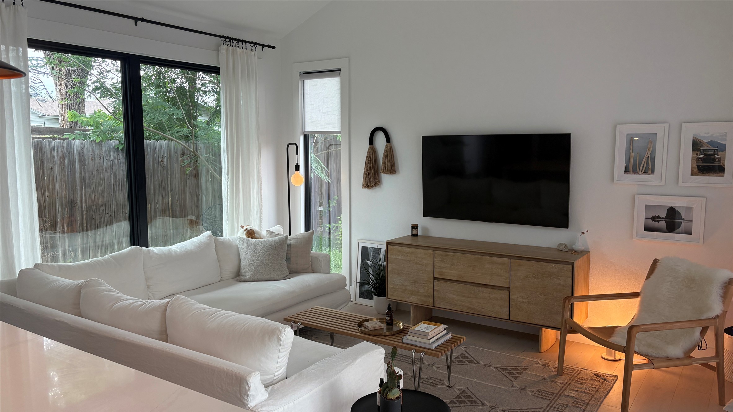 1816 Adina Street, Unit 2 Austin, TX 78721 - Photo 4 of 25 Vaulted ceilings accentuating the spacious living area, featuring large black-framed windows, a built-in entertainment console, and light-toned flooring