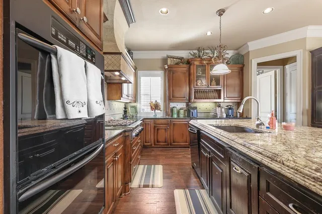 a kitchen with stainless steel appliances granite countertop a sink a stove and a wooden floors