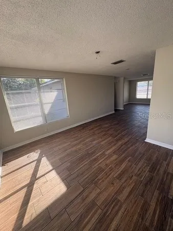 a view of empty room with window and wooden floor