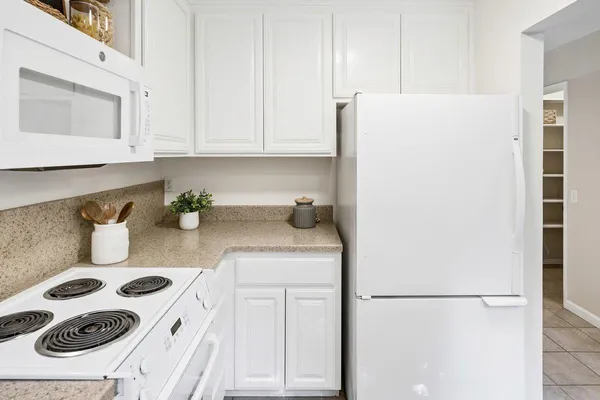 a kitchen with a refrigerator and white cabinets