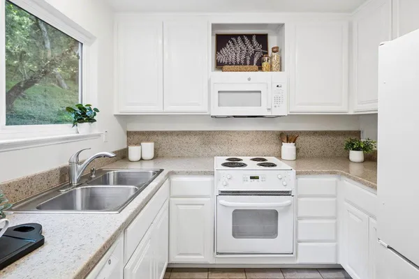 a kitchen with granite countertop white cabinets and white appliances